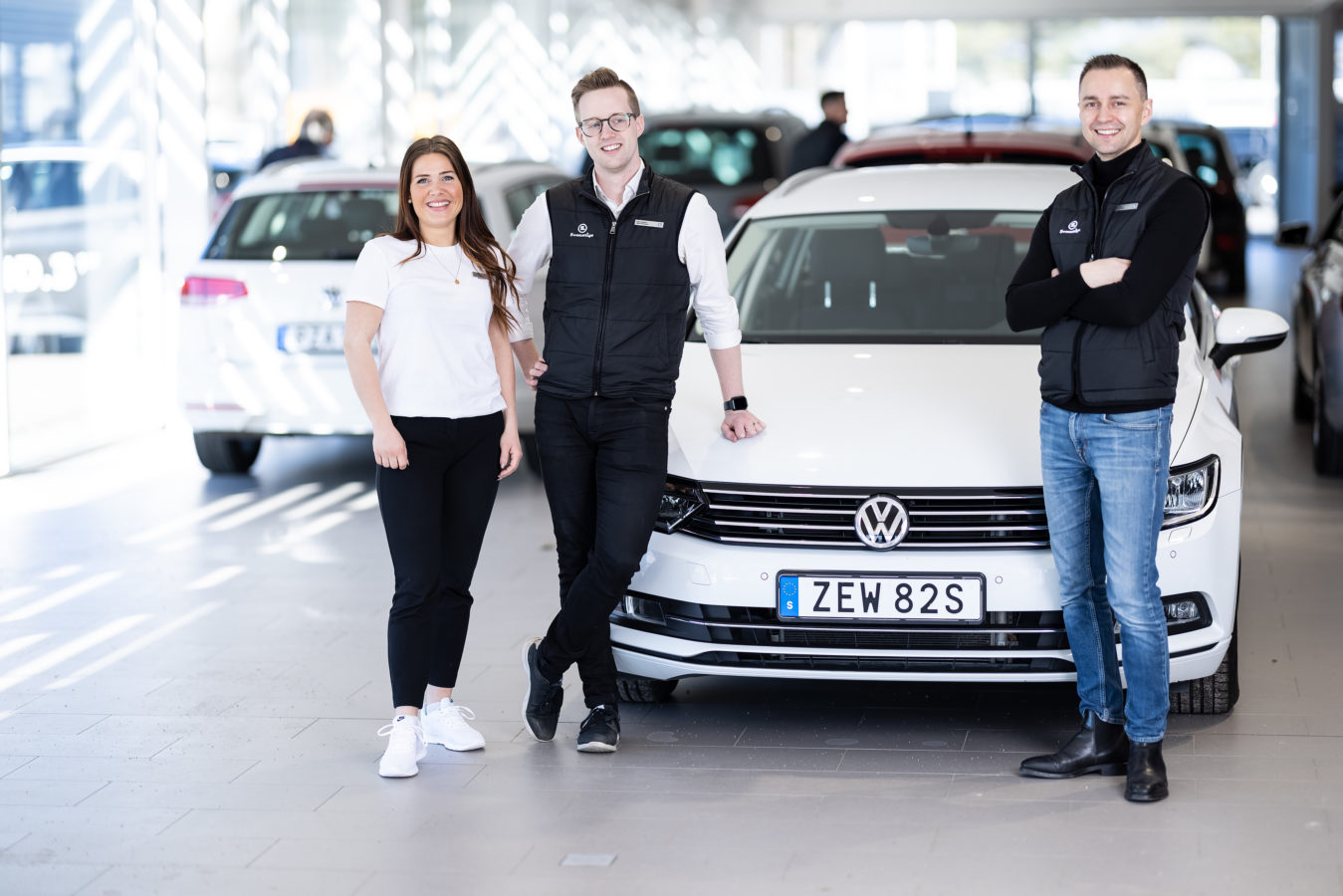 Tre personer står framför en Volkswagen